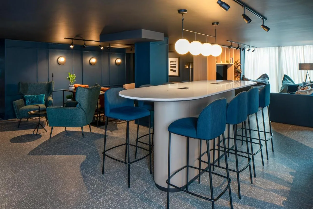 a kitchen with a bar with blue bar stools at Aparthotel Birmingham in Birmingham